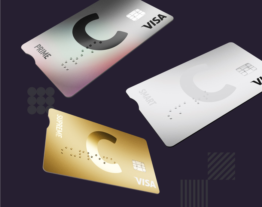 Trys kortelės su C logotipu ir VISA ženklu juda tamsiame fone, viena kortelė auksinė spalvos, kita balta, o dar kita pilka su vaivorykštės atspindžiu, teksto blokas viduryje.