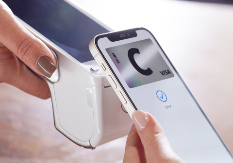 A smartphone above a contactless payment terminal, paying with a C prime card.