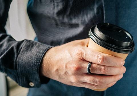 hand holding coffee cup and has ring on finger