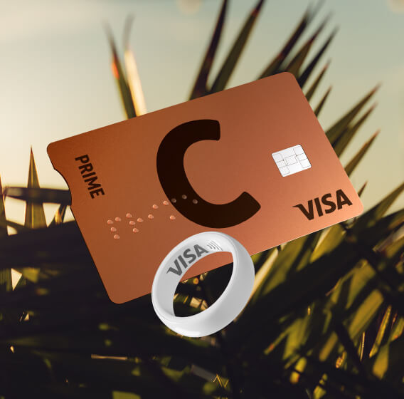 C prime lava VISA card and white payment ring with VISA logo against palm leaves at sunset.