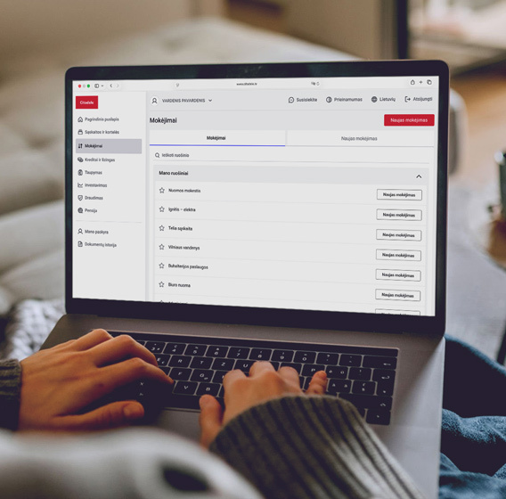 A person is holding a laptop displaying the new design of Citadele Online Bank.