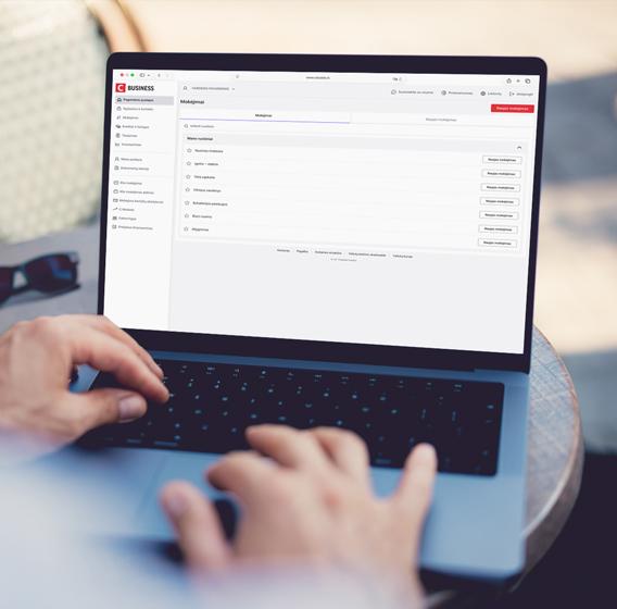 A person is holding a laptop displaying the new design of Citadele Online Bank.