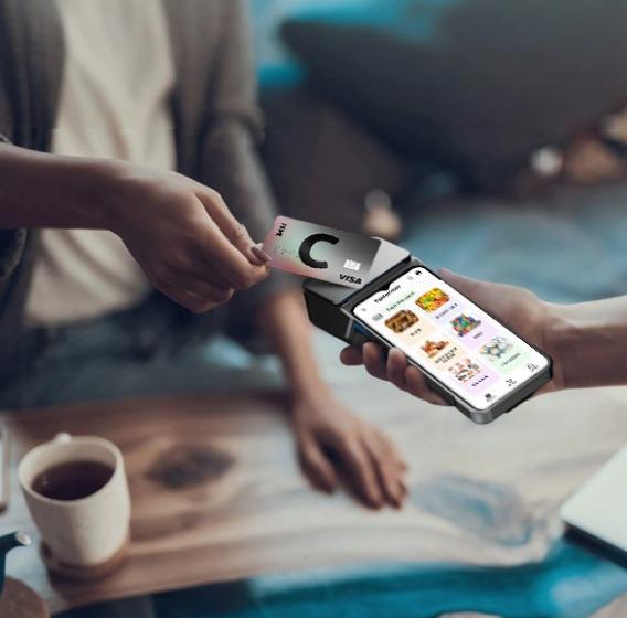 Client making a payment with a Landi M20 terminal using a payment card, with a table and a cup of coffee visible.