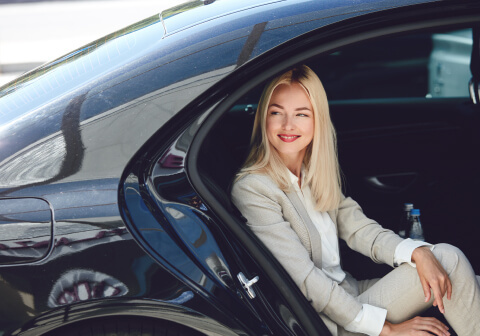 A girl sits in the back seat of a black car, enjoying the transfer provided by the Concierge service.