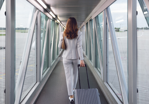 A person with a suitcase walks through the airport jet bridge, using the benefits of Fast Track.